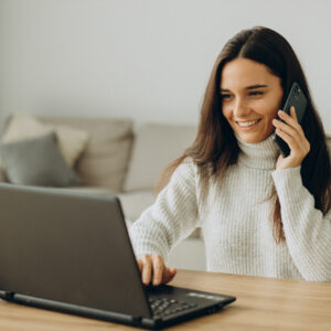 Femme qui travaille sur son ordinateur et qui téléphone avec une solution de centrale téléphonique efficace, 3CX